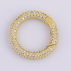 May include: A gold-toned ring with a double row of clear cubic zirconia stones. The ring is open and has a clasp closure.