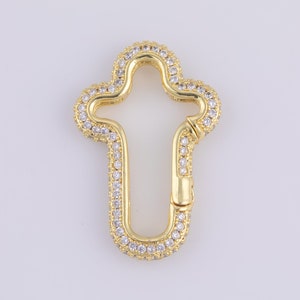 May include: Gold-toned cross-shaped clasp with clear cubic zirconia stones encrusted around the perimeter.