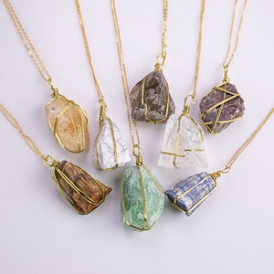 May include: A selection of gemstone necklaces. Each necklace has a raw, irregularly shaped stone wrapped in gold-coloured wire and suspended from a delicate gold chain. The stones vary in colour, including orange, white, brown, green, and purple.