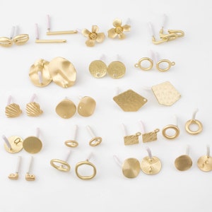 May include: Assortment of gold-toned earring findings and charms, including seashells, flowers, circles, squares, and hexagons.