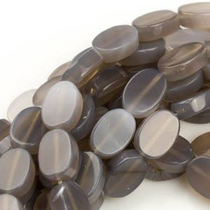 May include: A strand of oval-shaped gray agate beads. The beads have a smooth, polished finish and a translucent appearance.