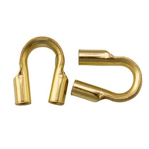 Puede incluir: Dos cierres de metal de color dorado para la elaboración de joyas. Los cierres están abiertos y listos para ser unidos a un collar o pulsera.