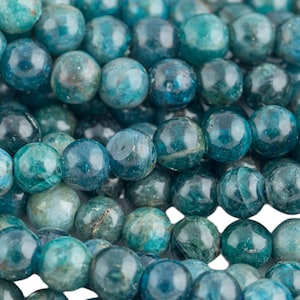 May include: A strand of blue apatite beads. The beads are round and have a smooth, polished finish. They are a light blue color with some darker blue streaks.