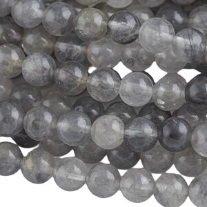 Könnte beinhalten: Eine Strähne grauer Rauchquarzperlen. Die Perlen sind rund und haben eine durchscheinende Optik.