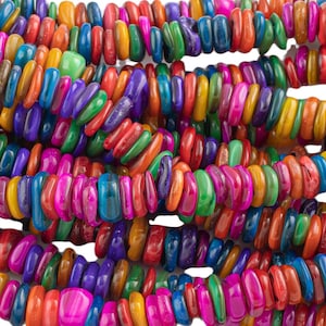 May include: A strand of colorful, multi-colored, wooden beads. The beads are flat and oval shaped. The beads are strung on a clear string.