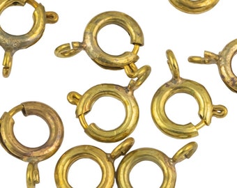Op de afbeelding: Een groep van 14 gouden metalen sprongringen. De ringen zijn allemaal even groot en hebben een veerbelaste sluiting.