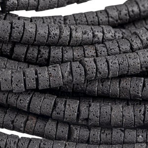 Könnte beinhalten: Eine Schnur aus schwarzen Lavasteinen. Die Perlen sind rund und haben eine raue, strukturierte Oberfläche.