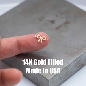 Può includere: Un ciondolo a forma di fiocco in oro pieno con due anelli a salto. 14K Gold Filled Made in USA.