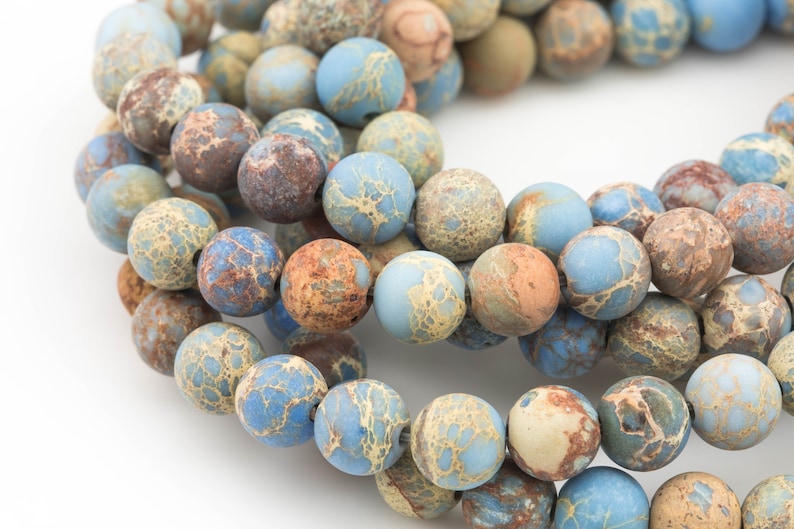 May include: A strand of blue, brown, and beige jasper beads. The beads are round and have a mottled pattern.
