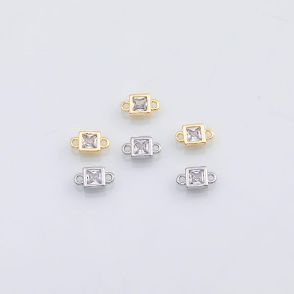 Puede incluir: Un conjunto de cinco conectores de joyería cuadrados con piedras transparentes facetadas en marcos de metal. Tres conectores son de tono dorado y dos de tono plateado, cada uno con pequeños aros circulares en los lados opuestos.