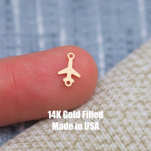 以下が含まれることがあります： ジャンプリングが付いた小さな金張りの飛行機チャーム。14K Gold Filled Made in USA.