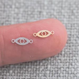 以下が含まれることがあります： 目は小さな円が中央にある、銀と金の2つの金属製のチャームです。チャームは指にあります。