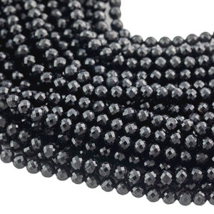 Può includere: Una collana di perle di pietra preziosa nera sfaccettata. Le perle sono rotonde e hanno una finitura lucida e lucidata.