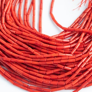 May include: A strand of bright red coral beads, each bead is a small cylinder shape.