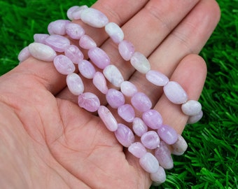 Puede incluir: Una hebra de cuentas de piedras preciosas de color rosa pálido y blanco. Las cuentas son de forma ovalada y tienen un acabado liso y pulido.