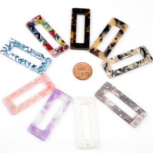 May include: Assortment of ten rectangular hair clips in various colors and patterns. The clips are made of plastic and have a smooth, glossy finish.
