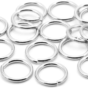Puede incluir: Un grupo de anillos de salto plateados, un tipo de anillo de metal utilizado en la fabricación de joyas.