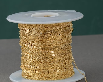 May include: A spool of gold-colored chain, wound around a white plastic spool. The chain is a delicate, oval-link style.