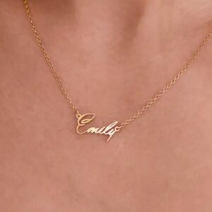 May include: A gold necklace with a cursive nameplate pendant that reads "Emily".