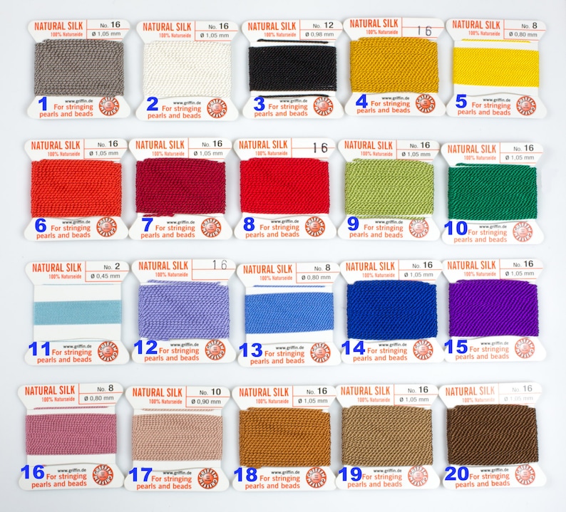 Pu&ograve; includere: Venti bobine di filo di seta naturale, ciascuna etichettata con un numero da 1 a 20. Il filo &egrave; disponibile in una variet&agrave; di colori, tra cui grigio, bianco, nero, giallo, rosso, verde, blu, viola, rosa e marrone. Le bobine sono disposte in quattro file di cinque. Ogni bobina &egrave; etichettata "Seta naturale" e include la dimensione e il numero del filo.