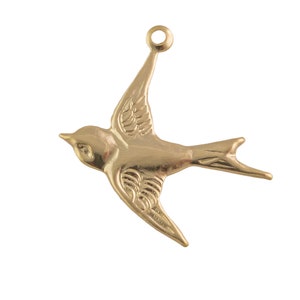 Puede incluir: Un amuleto de metal dorado en forma de golondrina volando.