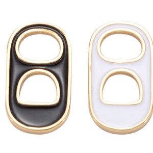 May include: Two gold-colored metal rings with a black and white enamel finish. Each ring has two holes.
