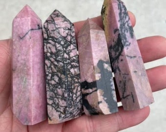 May include: Four pink and black polished gemstone points. The points are smooth and have a natural, striated pattern.