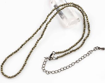 May include: A gold-toned necklace made of small, faceted beads. The necklace has a simple chain extender.