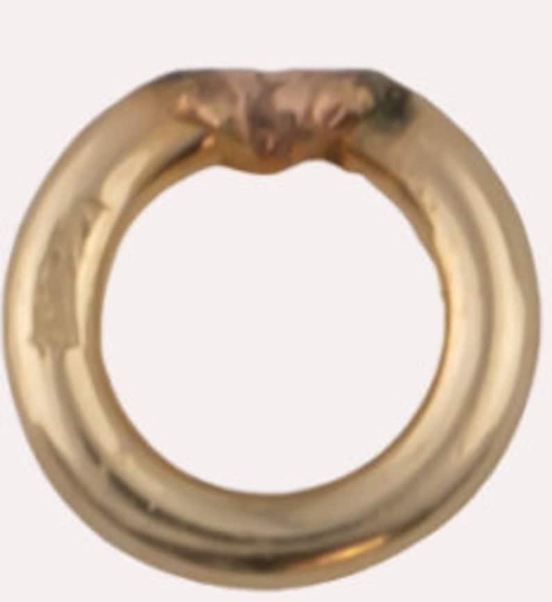 May include: A gold-toned metal ring with a smooth, rounded surface.