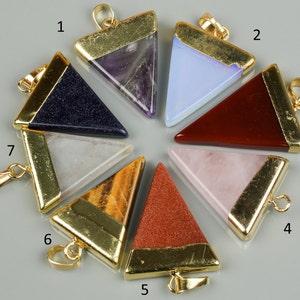 May include: Seven gold-rimmed triangular pendants with different coloured gemstones. The pendants are numbered 1 through 7.