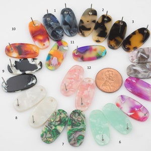 Könnte beinhalten: Zwölf Paare ovaler Ohrringe mit verschiedenen Mustern und Farben. Die Ohrringe sind aus Kunststoff und haben einen Stiftverschluss.