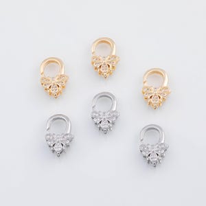 May include: Six decorative bee-shaped clasps. Three are gold-toned, and three are silver-toned. Each clasp features a bee design with sparkling crystal accents. The clasps are arranged on a white surface.