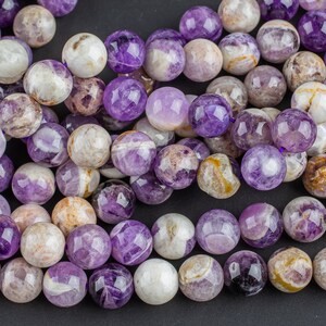 May include: A strand of purple and white amethyst beads. The beads are round and have a faceted finish.