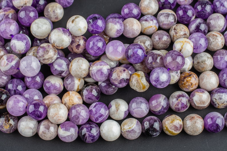May include: A strand of purple and white amethyst beads. The beads are round and have a faceted finish.