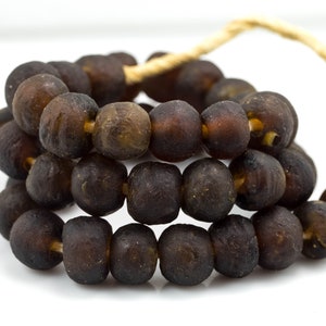 May include: A strand of dark brown amber beads strung on a natural fiber cord. The beads are round and have a matte finish.