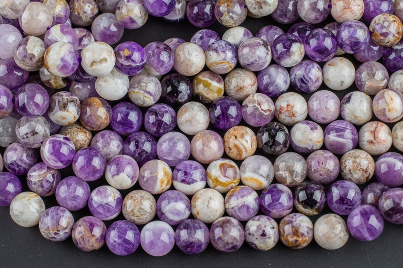 May include: A strand of round, purple amethyst beads with white and brown swirls. The beads are approximately 10mm in diameter.