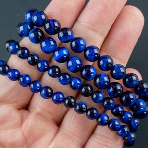 Puede incluir: Cuatro hileras de pulseras de cuentas de ojo de tigre azul. Las cuentas son redondas y tienen un acabado liso y pulido.