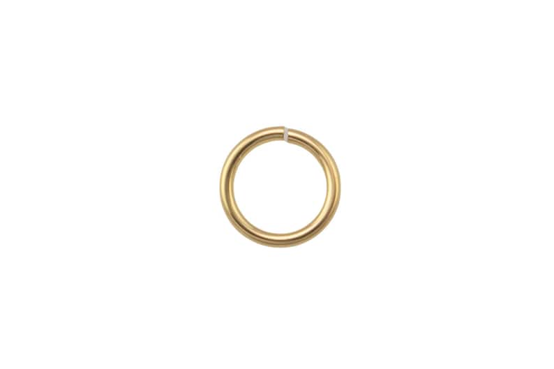 May include: A single, gold-colored jump ring, isolated on a white background. The ring is circular with a small opening, likely for jewelry making or crafts. The metal has a smooth, polished finish.
