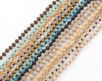 May include: A collection of beaded necklaces in various colors, including brown, blue, beige, and cream. The necklaces are made of different materials, including glass, wood, and metal.