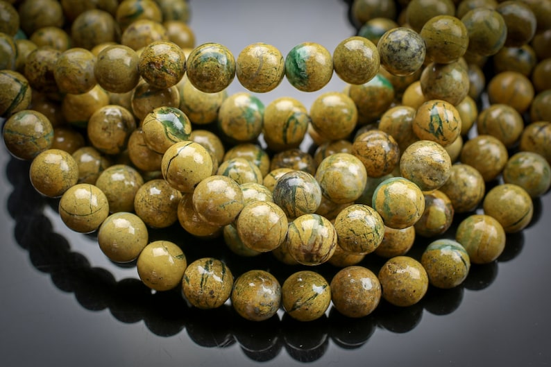 Peut inclure: Un brin de perles de jaspe jaune et vert. Les perles sont rondes et ont un aspect marbr&eacute;.