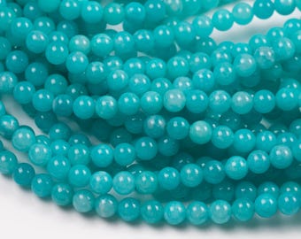 Peut inclure: Gros plan sur des brins de perles turquoise. Les perles sont rondes et ont une surface lisse et polie. Les perles sont enfilées ensemble, créant un motif fluide. La couleur est un turquoise vif et saturé, idéal pour la création de bijoux.