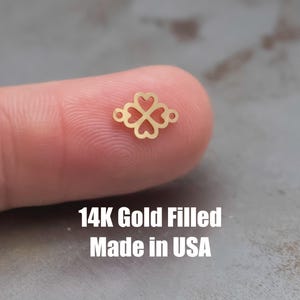 May include: A gold-filled charm featuring a four-leaf clover design with open hearts. 14K Gold Filled Made in USA.