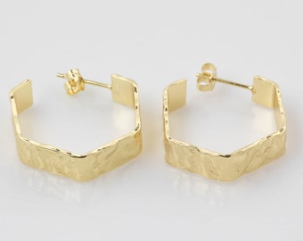 May include: A pair of gold hexagonal hoop earrings with a textured finish.