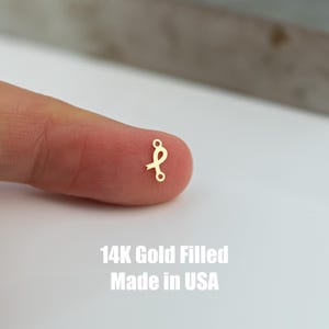May include: A small gold-filled ribbon charm with a loop on each end. 14K Gold Filled Made in USA.