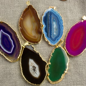 May include: Six agate slices with gold trim, each with a different colour and pattern. The colours include purple, brown, blue, pink, black, and green.