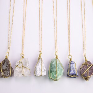 May include: A selection of gemstone necklaces. Each necklace has a unique, irregularly shaped stone wrapped in gold-coloured wire and suspended from a delicate gold-coloured chain. The stones vary in colour, including shades of brown, white, green, and purple.