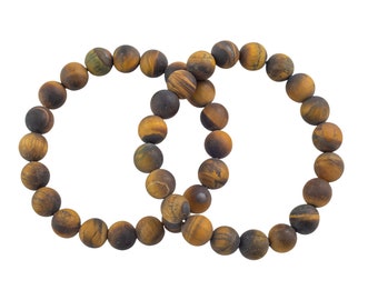 May include: Two beaded bracelets made of tiger's eye stones. The bracelets are circular, with each bead displaying a mix of brown, gold, and black hues. The beads are round and appear to be strung together on an elastic cord.