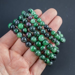 May include: A stack of green and black gemstone bracelets with round beads.