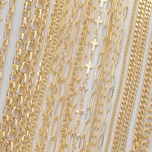 May include: A collection of gold-colored necklaces with various chain styles. The necklaces include curb chains, rolo chains, and chains with cross pendants. The chains are displayed against a white background.