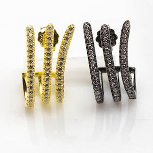 May include: A pair of ear cuffs, one gold and one black, with a row of small clear stones on each cuff.